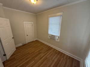 Spare room featuring visible vents, ornamental molding, wood finished floors, cooling unit, and baseboards