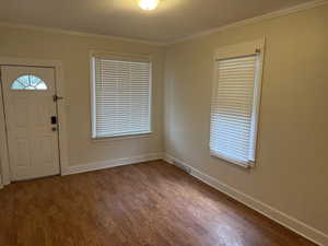 Entryway with visible vents, crown molding, baseboards, and dark wood-style flooring