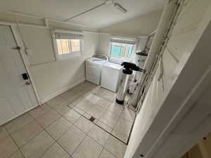 Laundry area featuring light tile patterned floors, laundry area, plenty of natural light, and washer and clothes dryer