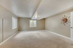 Empty room with baseboards, light carpet, and a textured ceiling