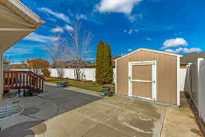 View of patio with an outbuilding, a storage shed, and a fenced backyard