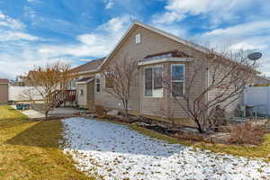 View of snow covered exterior featuring a patio area, a lawn, and fence