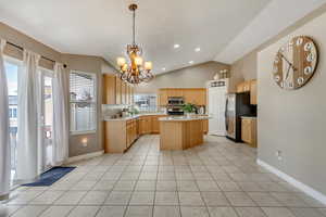 Kitchen with light brown cabinetry, a kitchen island, stainless steel appliances, and light countertops