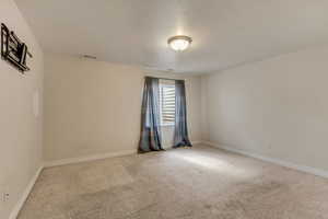 Carpeted spare room with visible vents and baseboards