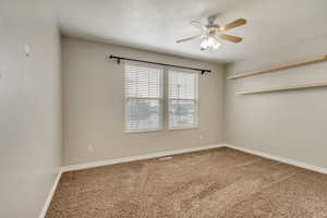 Carpeted empty room with visible vents, a textured ceiling, a ceiling fan, and baseboards