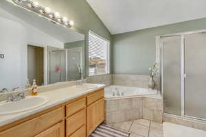 Full bath with a sink, lofted ceiling, a stall shower, and tile patterned floors