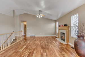 Living area with visible vents, baseboards, light wood-style flooring, and a tile fireplace