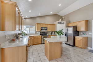 Kitchen featuring a sink, light tile patterned floors, appliances with stainless steel finishes, and light brown cabinetry