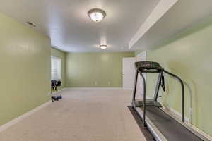 Workout area featuring baseboards, visible vents, and a textured ceiling