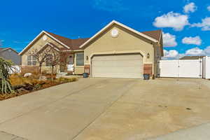 Single story home featuring stucco siding, driveway, a gate, a garage, and brick siding