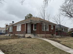 View of front of house with brick siding, a front lawn, and fence