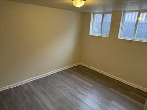 Empty room with dark wood-type flooring, baseboards, and a textured ceiling