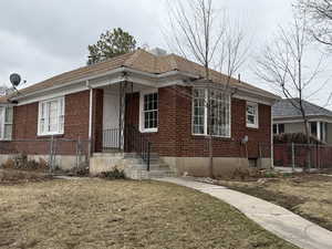 View of front of home featuring brick siding, a front yard, and fence