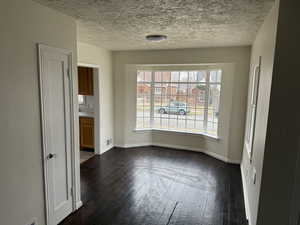 Unfurnished dining area featuring visible vents, baseboards, dark wood-type flooring, and a textured ceiling