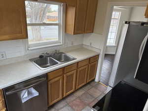 Kitchen with a sink, plenty of natural light, appliances with stainless steel finishes, and brown cabinetry