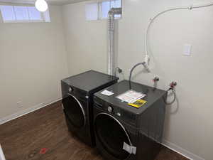 Washroom featuring baseboards, dark wood-type flooring, laundry area, and washer and clothes dryer