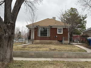 View of home's exterior with brick siding, a shingled roof, fence, a chimney, and a gate