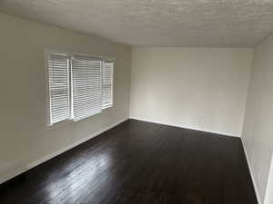 Spare room featuring hardwood / wood-style floors, baseboards, visible vents, and a textured ceiling