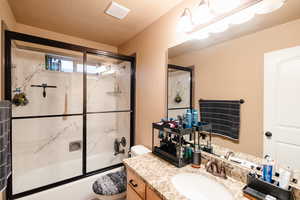 Full bathroom featuring visible vents, toilet, vanity, enclosed tub / shower combo, and a textured ceiling