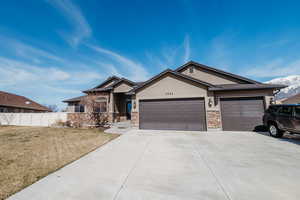 Ranch-style home with fence, stucco siding, concrete driveway, a garage, and stone siding