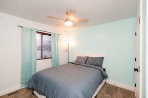 Carpeted bedroom featuring visible vents, ceiling fan, a textured ceiling, and baseboards