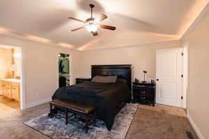 Bedroom with lofted ceiling, light colored carpet, visible vents, and ensuite bathroom