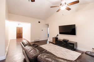 Living room with lofted ceiling, wood finished floors, visible vents, and baseboards