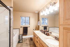 Full bath featuring a sink, a garden tub, a shower stall, and a textured ceiling