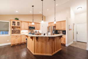 Kitchen featuring a large island, a breakfast bar area, appliances with stainless steel finishes, and light brown cabinetry