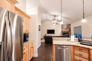 Kitchen featuring lofted ceiling, light brown cabinets, freestanding refrigerator, and ceiling fan