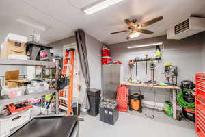 Interior space with a workshop area, finished concrete flooring, and ceiling fan