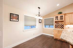 Unfurnished dining area with dark wood-style floors, visible vents, baseboards, lofted ceiling, and recessed lighting