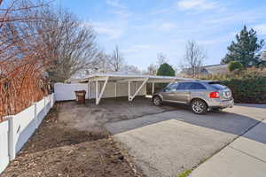 View of parking featuring driveway and fence