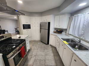 Kitchen featuring a sink, stainless steel appliances, light countertops, white cabinets, and under cabinet range hood