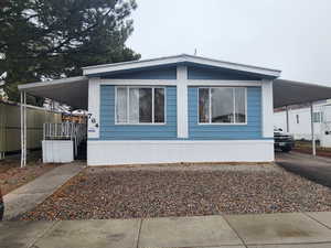 View of property exterior with an attached carport, covered porch, and aphalt driveway