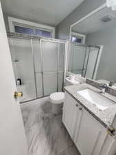 Full bath featuring visible vents, toilet, a shower with shower door, marble finish floor, and vanity