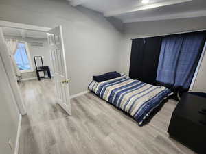 Bedroom with beamed ceiling, baseboards, and light wood finished floors