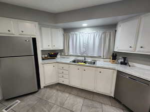 Kitchen with visible vents, a sink, light countertops, white cabinets, and appliances with stainless steel finishes