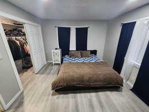 Bedroom featuring a walk in closet, baseboards, a closet, and wood finished floors