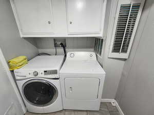 Washroom featuring washing machine and clothes dryer and cabinet space