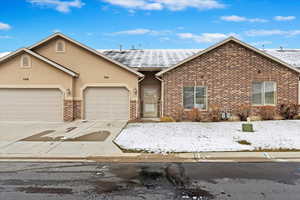 Ranch-style home featuring stucco siding, driveway, an attached garage, a shingled roof, and brick siding