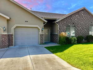 Ranch-style home featuring concrete driveway, an attached garage, a front yard, stucco siding, and roof with shingles