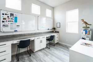 Home office with built in desk, light wood-type flooring, and baseboards