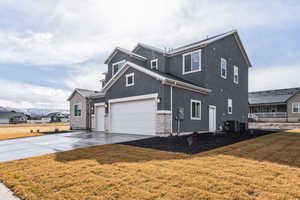 View of front of house featuring a front yard, central AC unit, driveway, an attached garage, and stucco siding