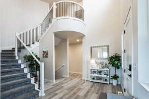 Foyer featuring visible vents, wood finished floors, baseboards, and a towering ceiling