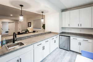 Kitchen with a sink, pendant lighting, white cabinets, and light wood finished floors