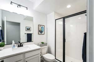 Bathroom featuring recessed lighting, toilet, a stall shower, and vanity