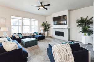 Living area with carpet flooring, a fireplace, a ceiling fan, and baseboards