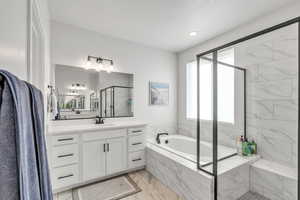 Bathroom featuring marble finish floor, a stall shower, vanity, and a garden tub