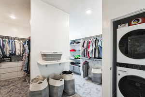 Clothes washing area featuring laundry area, stacked washing maching and dryer, and carpet floors